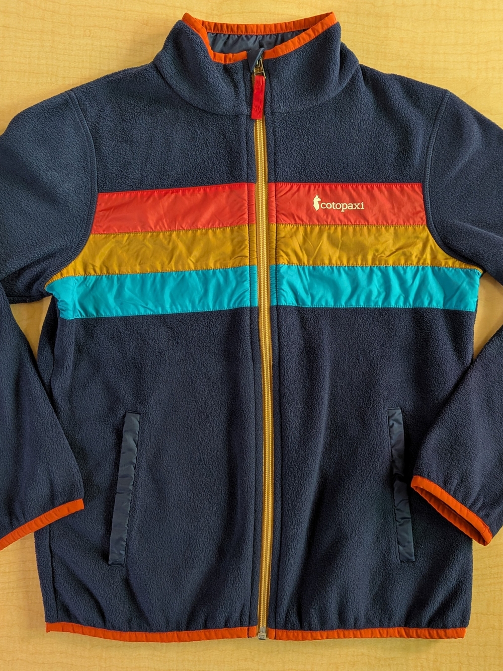 Cotopaxi Navy Kids Fleece Jacket with Red, Yellow & Teal Chest Stripes
